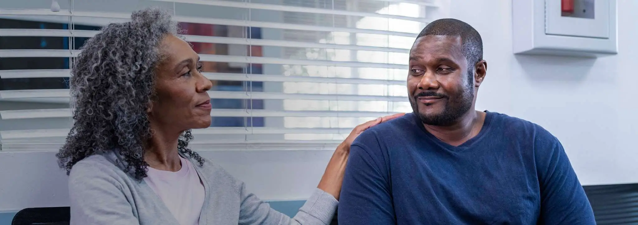 A young man and his caregiver sitting in a doctor’s office