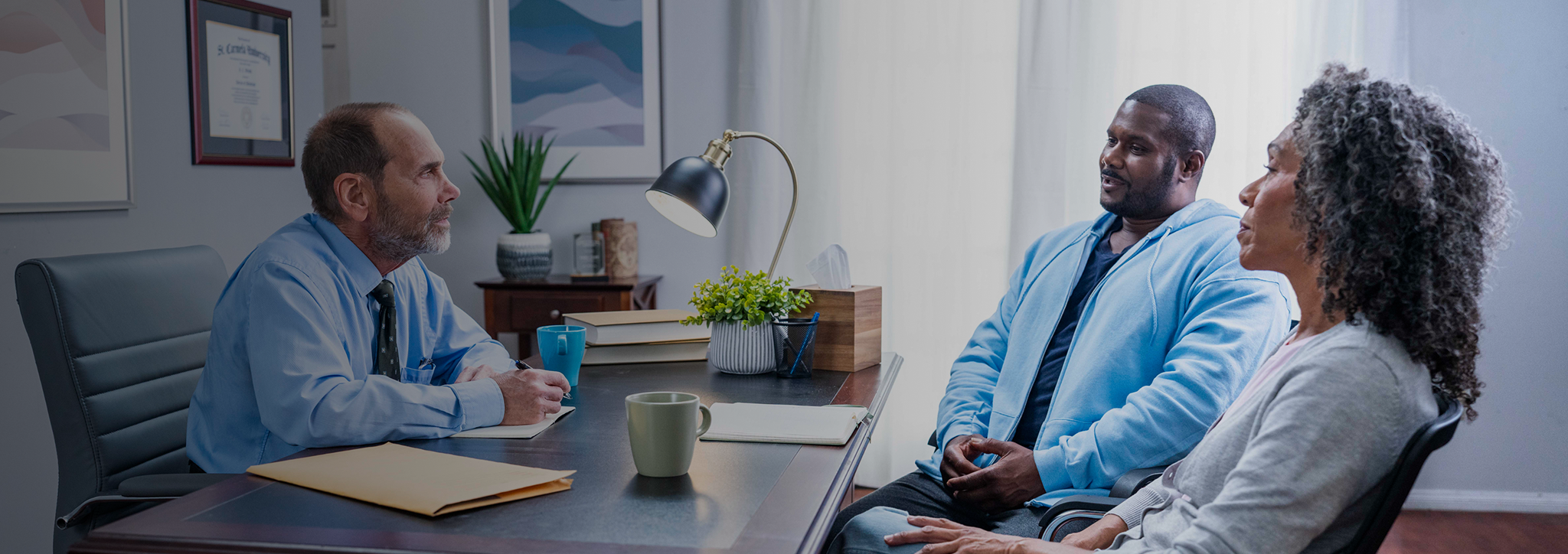 A patient and his caregiver having a conversation with a doctor